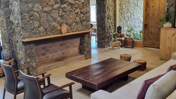 A lobby with a stone wall, a fireplace, seating area, and a sign indicating the exit.