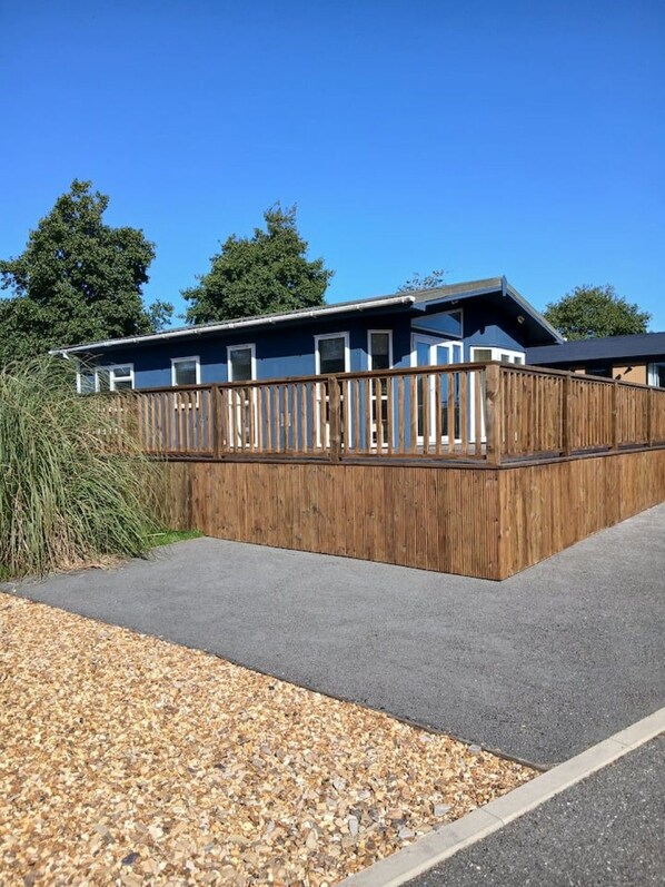 A modern two-story building with a wooden deck and a paved driveway.
