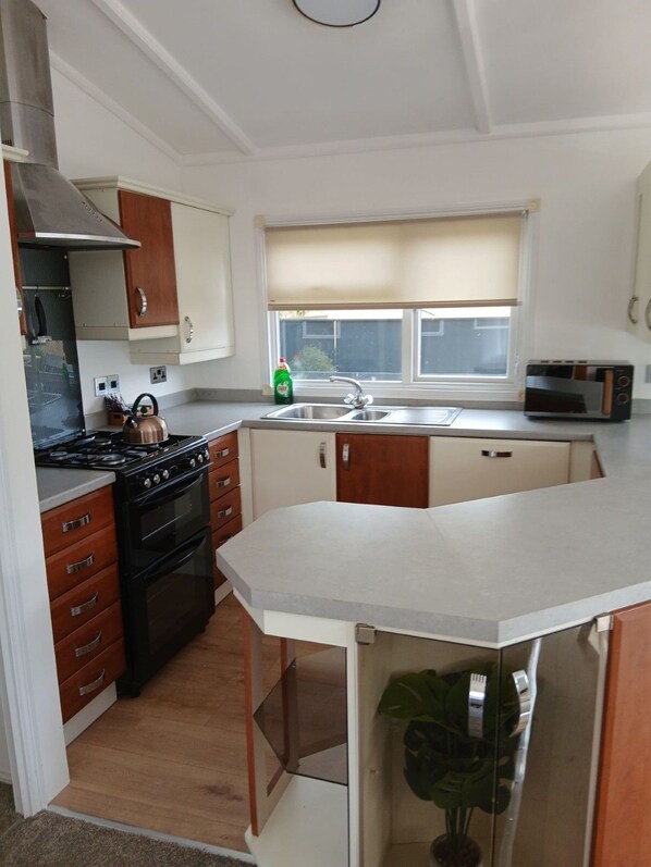 A kitchen with a stove, oven, microwave, and a window with a view.