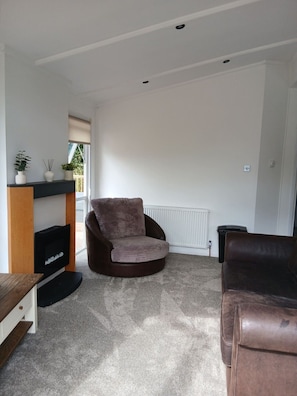 A living room with a brown leather sofa, a black entertainment unit, and a radiator.