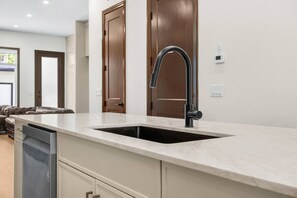 A kitchen with a built-in sink, a modern faucet, and a countertop. - The Hearth | 3 Bed | Garage | Min to DT (Calgary)