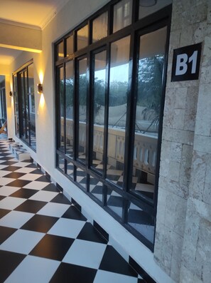 A hotel corridor with checkered flooring, large windows with a view of the outdoors, and a sign indicating room B1. - Spacious and Elegant 2-bedroom apartment with AC in Diani Beach (Diani Beach)