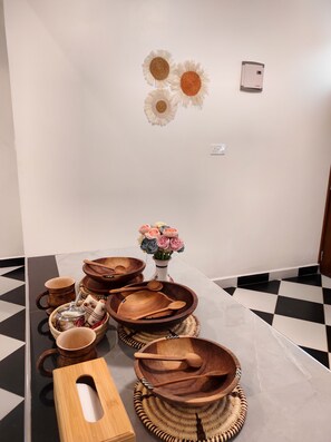 A room with a checkered floor, a table with wooden bowls and a wooden box, and a wall with a power outlet and wall art. - Spacious and Elegant 2-bedroom apartment with AC in Diani Beach (Diani Beach)