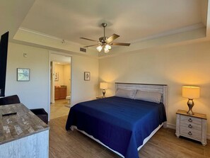 A bedroom with a bed, bedside lamps, a ceiling fan, and a view into the bathroom. - Coastal Condo - Near Beach - Bonita Springs (Bonita Springs)