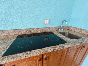 Una cocina con estufa integrada, un lavamanos y armarios de madera.