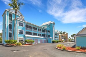 A multi-story hotel with a blue exterior, multiple balconies, and a parking area. - Bright Studio - Gulf Access - Bonita Springs (Bonita Springs)