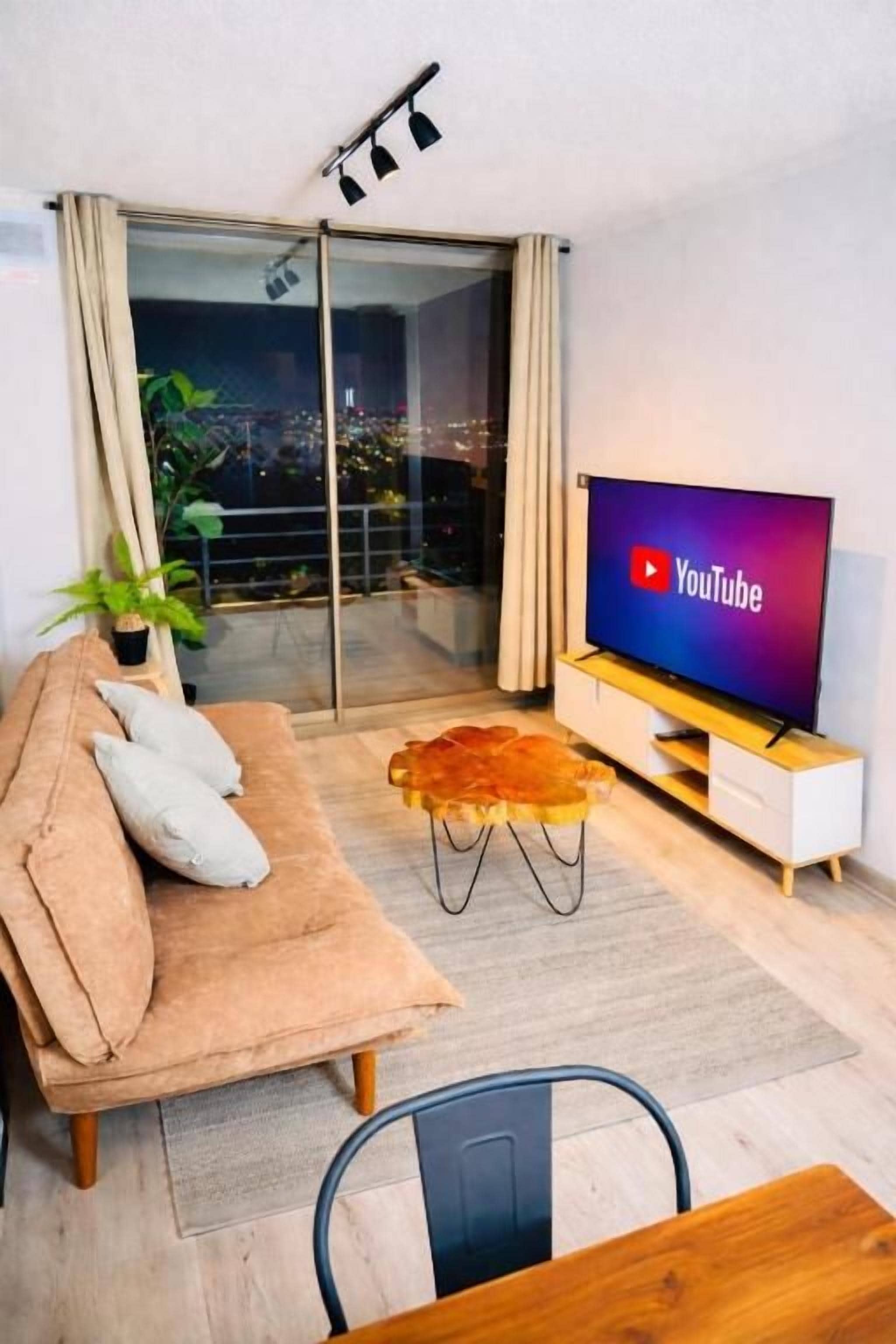 Ett vardagsrum med en soffa, ett soffbord, en tv och en skjutdörr i glas som leder ut till en balkong.