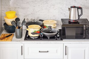 A kitchen with a stove, pots, a kettle, and a microwave. - Apartments Piramit in Tashkent (Tashkent)