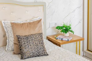 A bed with a headboard, two pillows, a bedside table with a plant, and a book. - Apartments Piramit in Tashkent (Tashkent)