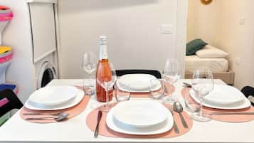 A dining table set with plates, cutlery, and wine glasses, with a bottle of wine in the center.