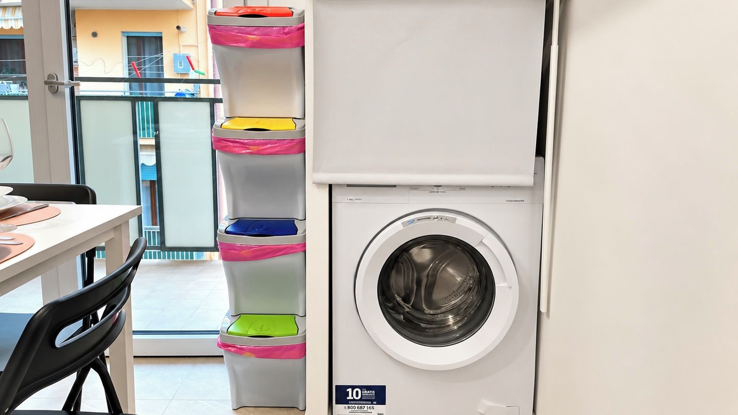 A compact laundry area with a front-loading washing machine and a set of multi-colored hanging laundry baskets.
