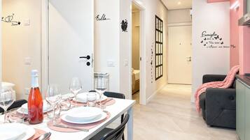 A dining area with a table set for four, a bottle of wine, and empty wine glasses.