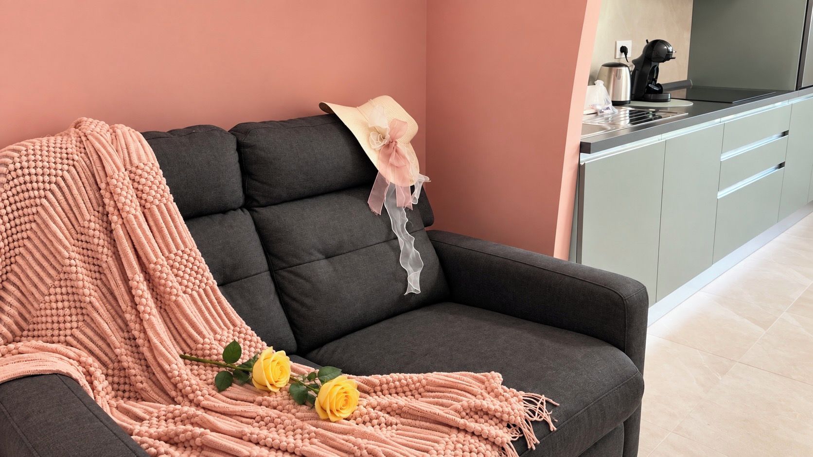 A modern living room with a sofa, a decorative blanket, and a hat on the backrest.