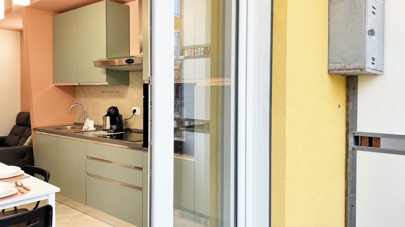 A compact kitchen with a coffee machine, a sink, and a dining area with a table set for two.
