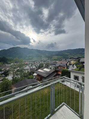 Un quartier résidentiel avec des maisons, un balcon et un paysage montagneux en arrière-plan.
