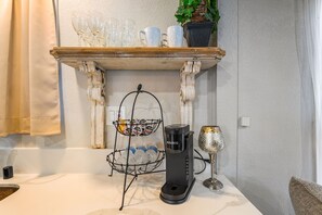 Ett köksutrymme med en kaffebryggare, ett vinglas och en vattenautomat på bänkskivan.