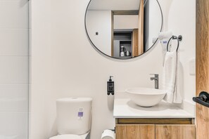 Ein modernes Badezimmer mit einem runden Spiegel, einem Waschbecken und einer Toilette.