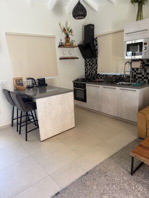 A modern kitchen with a central island, a stove, a microwave, and a sink.