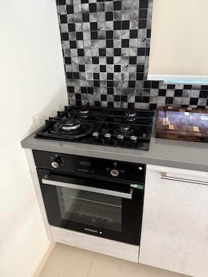 Een keuken met een zwart-wit schouderblad, een gasfornuis en een oven.