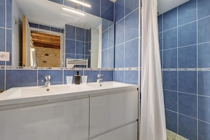 A bathroom with a double sink, a mirror, and blue tiled walls. - Room 'Chambre Lune' with Shared Pool, Wi-Fi and Air Conditioning - Table d'Hôtes (Salignac Eyvigues)