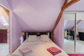 A bedroom with a sloped ceiling, a bed with pillows, and a view of the adjacent room through a glass door. - Room 'Chambre Etoile' with shared pool, Wi-Fi and air conditioning - Table d'Hôte (Salignac Eyvigues)