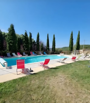 A swimming pool with lounge chairs and tall trees in the background. - Room 'Chambre Soleil' with Shared Pool, Wi-Fi and Air Conditioning (Salignac Eyvigues)