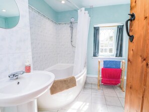Ein Badezimmer mit einer Badewanne, einem Waschbecken, einer Dusche und einem Fenster mit Vorhängen.