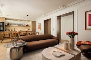 Ein modernes Wohnzimmer mit einem braunen Sofa, einem Essbereich mit Holzmöbeln und einer Küche im Hintergrund.