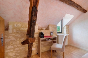 A cozy attic room with exposed stone walls, a wooden beam, a small table with a kettle, and a chair. - Room 'Chambre Romantique' with Shared Pool, Wi-Fi and Air Conditioning - Table d'Hôte (Salignac-Eyvigues)