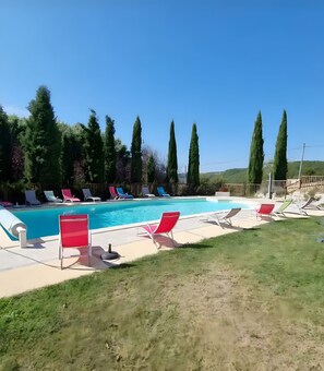 A swimming pool with lounge chairs and tall trees in the background. - Room 'Chambre Azur' with Shared Pool, Wi-Fi and Air Conditioning (Salignac-Eyvigues)