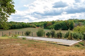 A fenced outdoor area with a gravel path, surrounded by dense trees and a grassy field. - Room 'Chambre Azur' with Shared Pool, Wi-Fi and Air Conditioning (Salignac-Eyvigues)