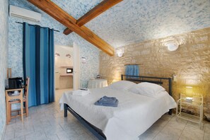 Ein Schlafzimmer mit Bett, Schreibtisch, Stuhl und einer Steinwand.