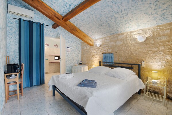 Ein Schlafzimmer mit Bett, Schreibtisch, Stuhl und einer Steinwand.
