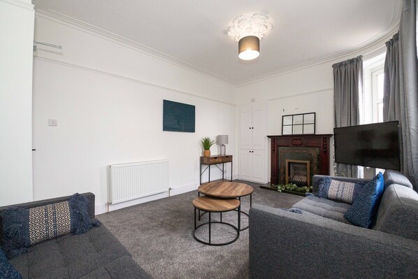 Ein modernes Wohnzimmer mit Kamin, Fernseher und einer gemütlichen Sitzecke.
