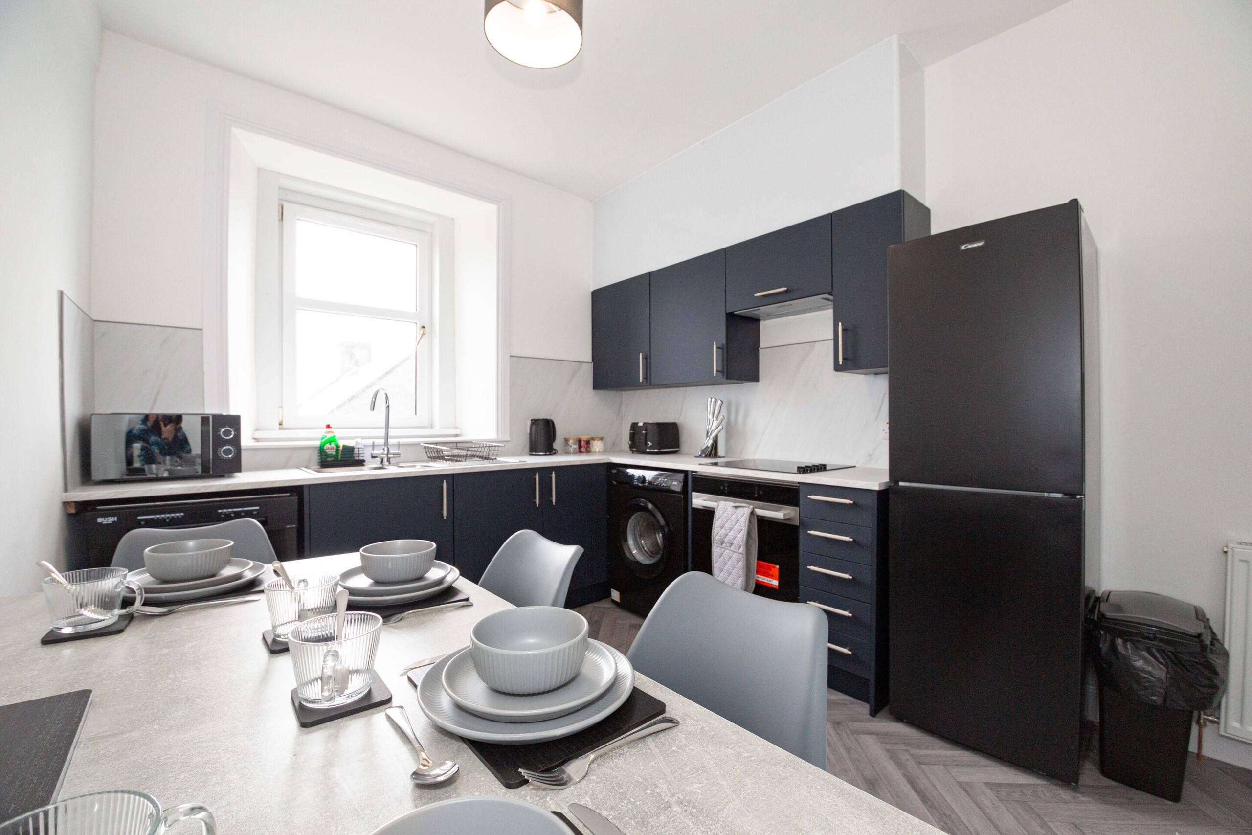 A modern kitchen with dark cabinets, a built-in oven, and a large refrigerator.