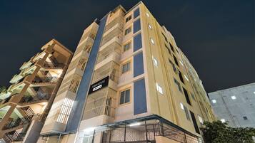 A multi-story building with balconies and a sign indicating it is a serviced apartment.