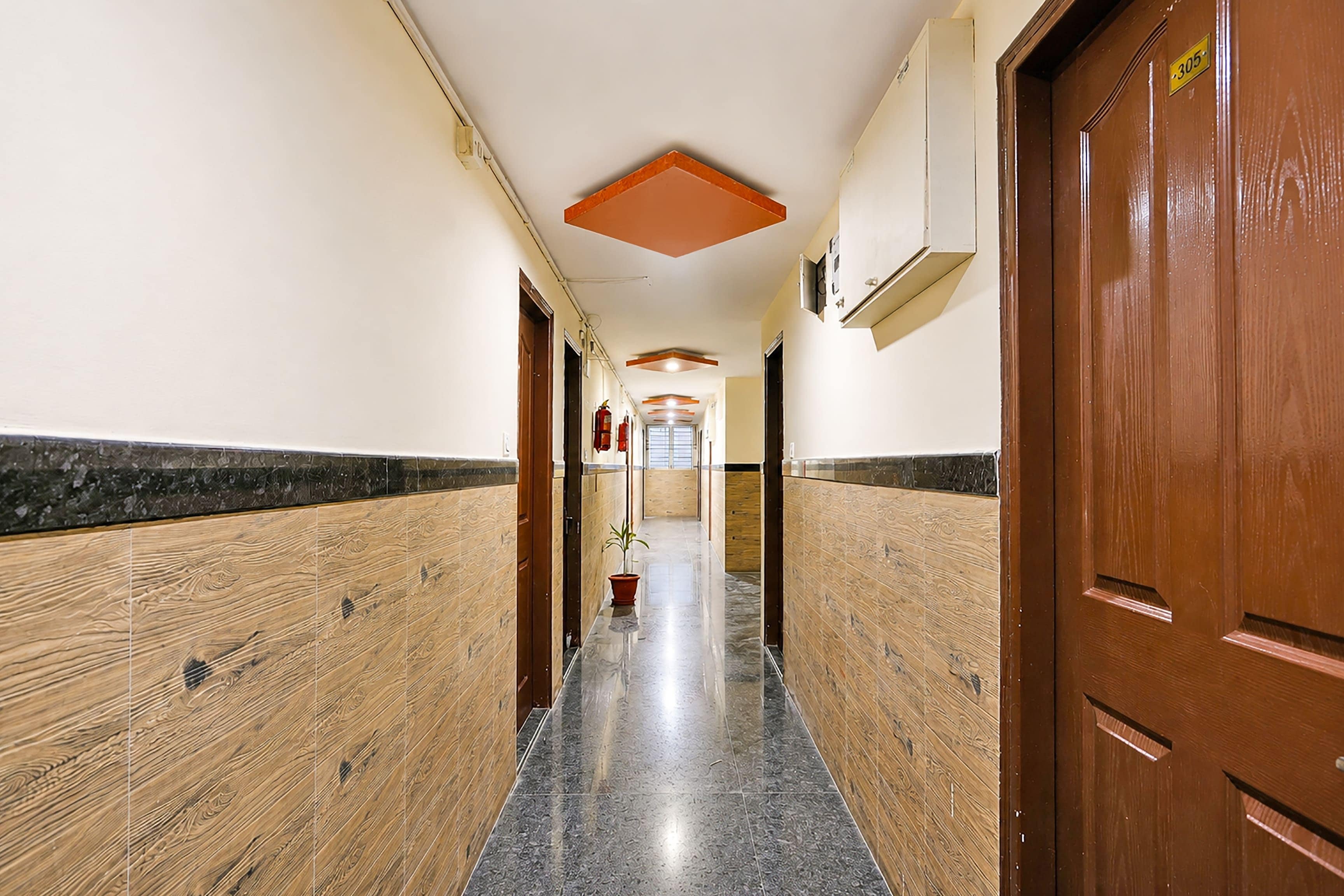 A hallway with wooden paneling, a tiled floor, and doors on both sides.