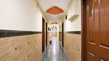 Un couloir aux murs lambrissés, doté d’un sol carrelé et de portes de part et d’autre.