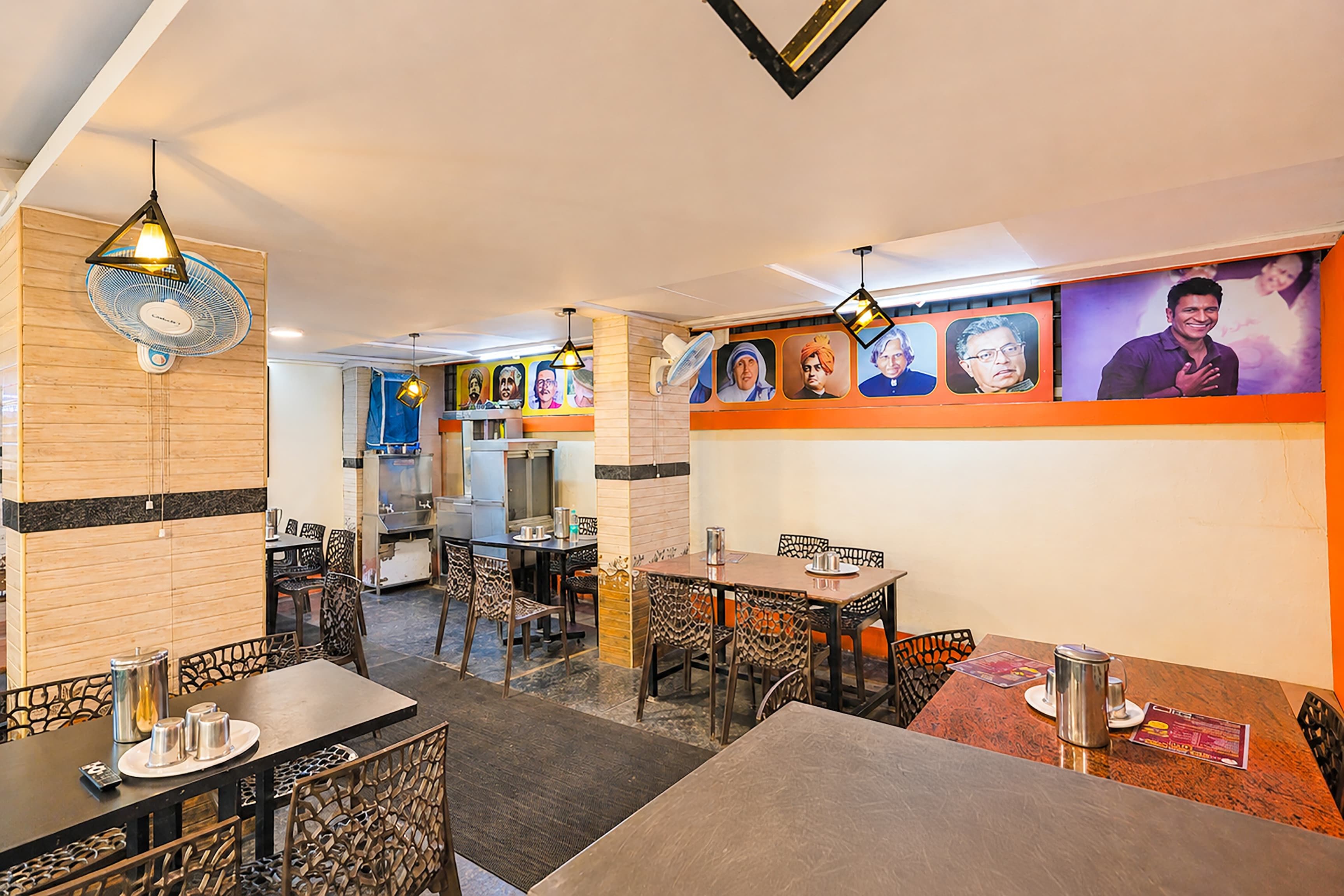 A restaurant interior with tables, chairs, and a wall with portraits.