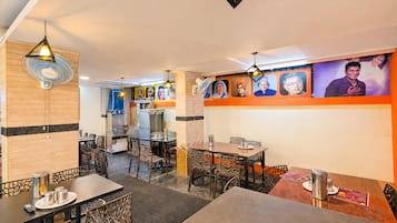 A restaurant interior with tables, chairs, and a wall with portraits.
