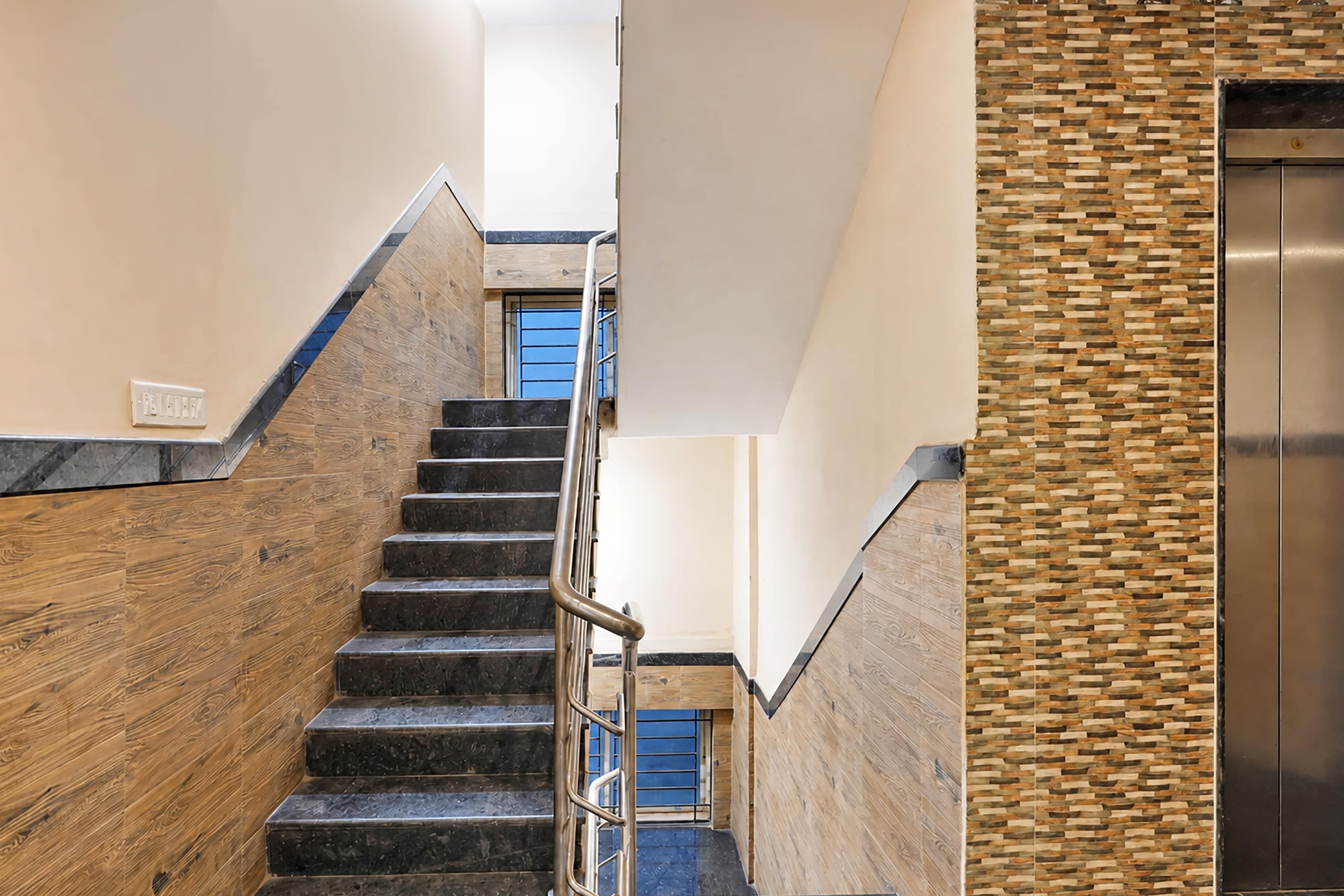 A modern staircase with a metal handrail leading to a blue door.