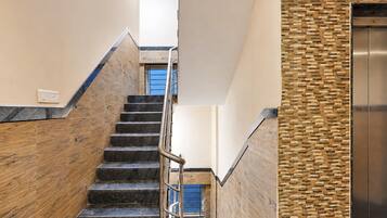 A modern staircase with a metal handrail leading to a blue door.