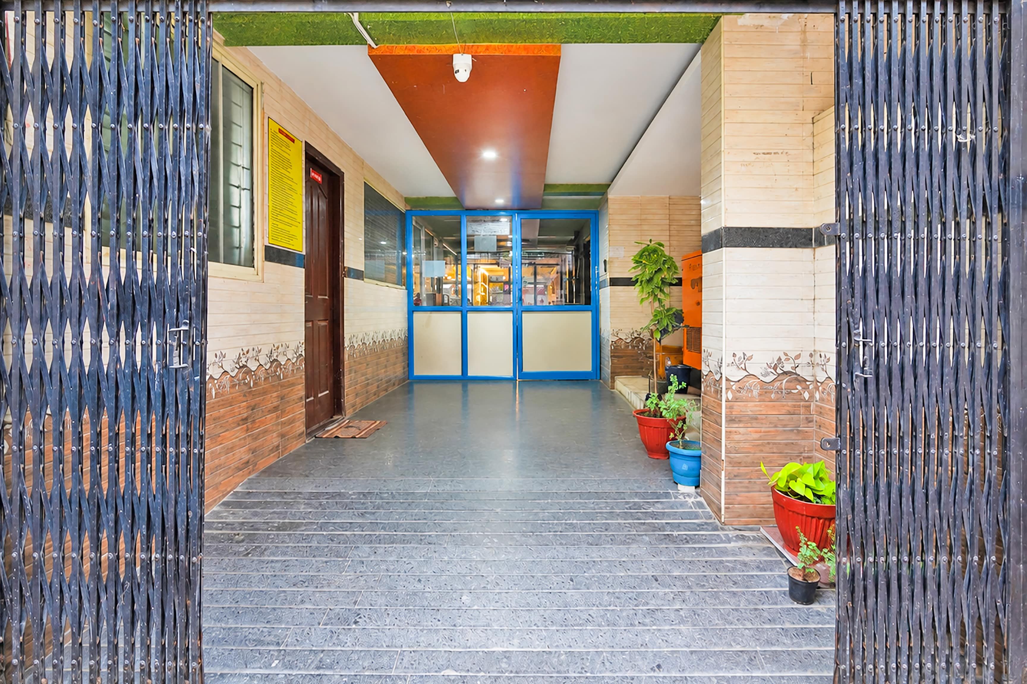 A hallway with a blue-framed door, potted plants, and a tiled floor.