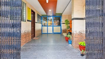 A hallway with a blue-framed door, potted plants, and a tiled floor.