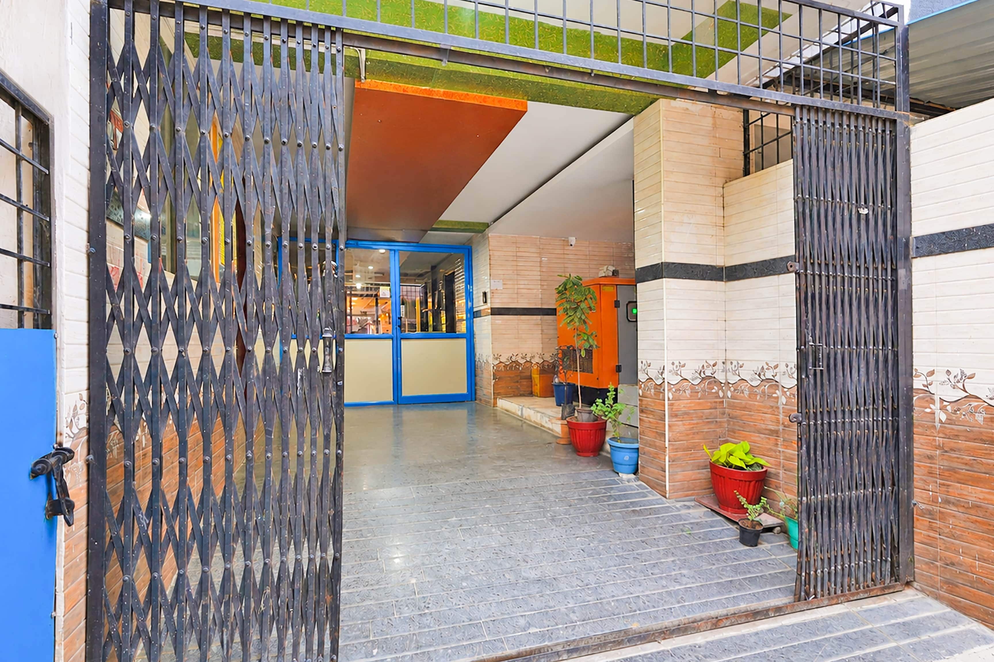 Una entrada protegida por un cerco de metal, una puerta azul y macetas con plantas.