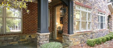 A stone house with a brick facade, a covered porch, and a well-maintained garden.