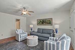 A living room with a gray sofa, striped armchairs, a round coffee table, and a ceiling fan. - War Eagle Manor:Your Auburn Getaway (Auburn)