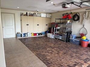 Eine Garage mit Stauraumschränken, einer Werkbank sowie verschiedenen Werkzeugen und Materialien.