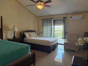 Habitación de hotel con cama, una silla, ventilador de techo y vistas al exterior.