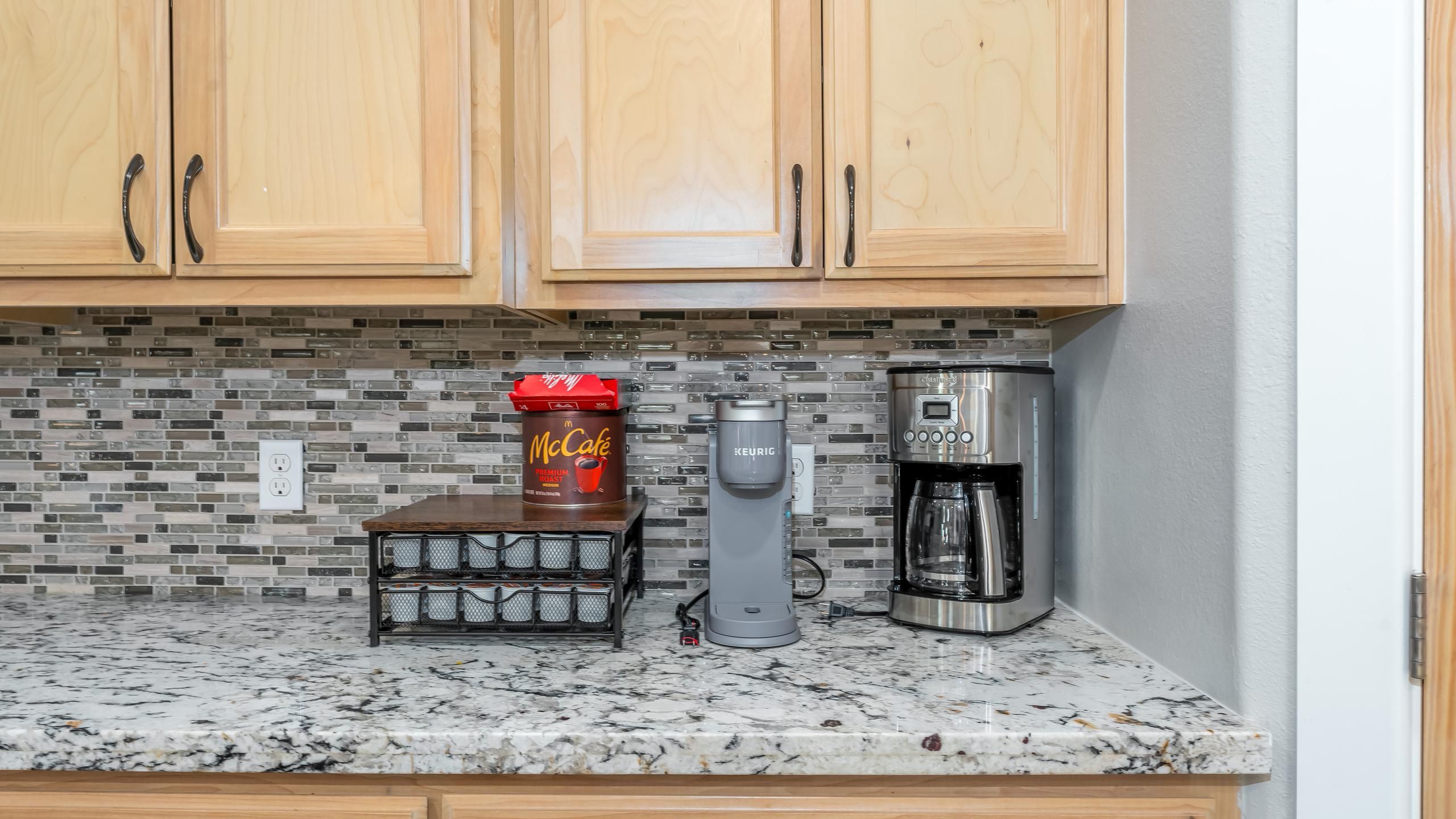 Une cuisine avec des meubles en bois, une machine à café, une machine Keurig et une tasse à café McCafé.